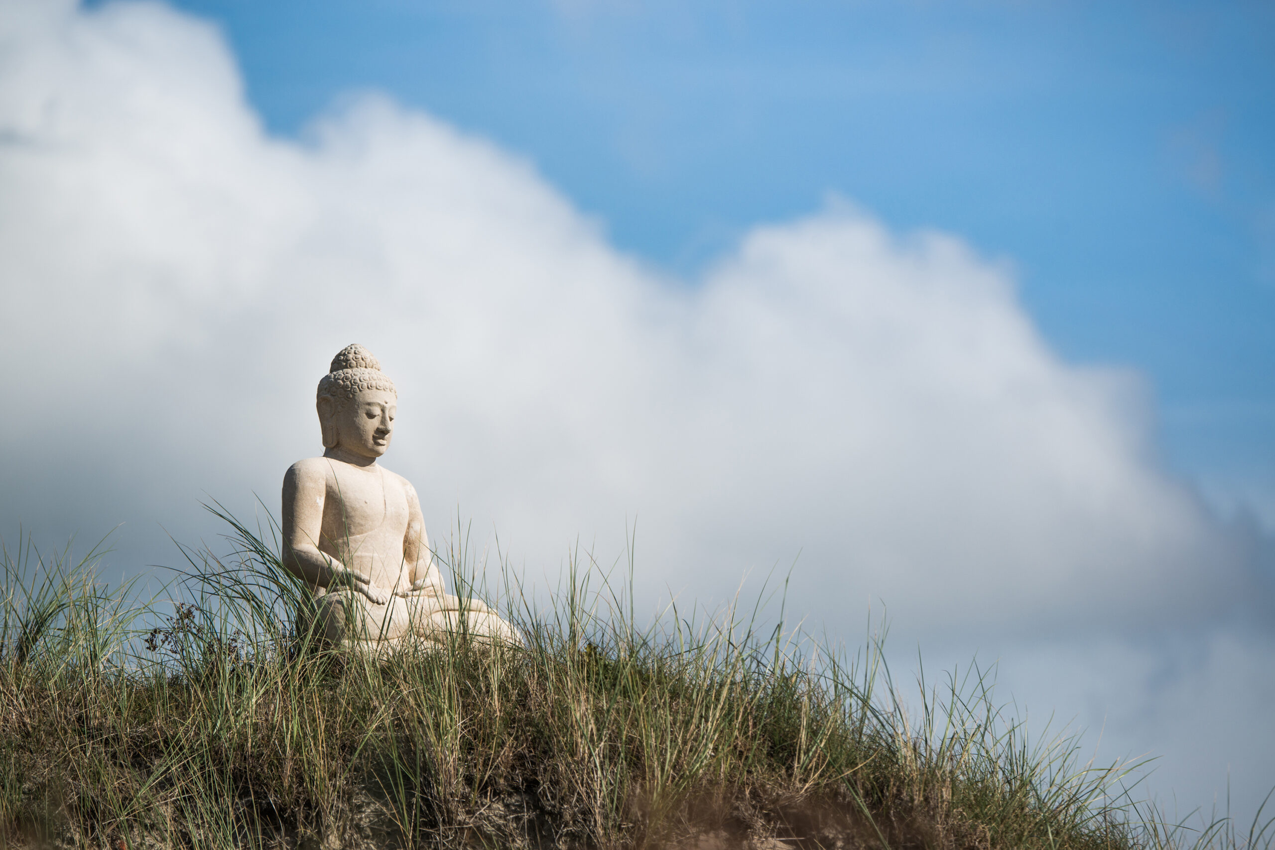Buddha-Figur auf einer Düne als Symbol für Achtsamkeit